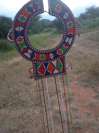 A beaded Maasai collar in red, blue, white and green hanging outdoors