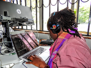 A developer with headphones working on a laptop in front of a large monitor